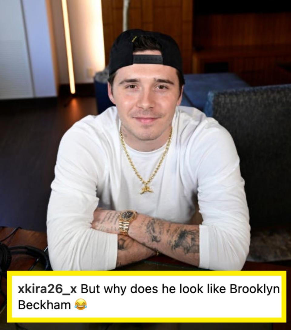 Brooklyn sitting at a desk with hands clasped, wearing a cap, and a watc