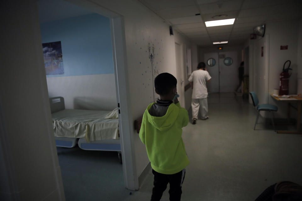 A boy watches medical staff as he stands in a corridor in the pediatric unit of the Robert Debre hospital, in Paris, France, Tuesday, March 2, 2021. (AP Photo/Christophe Ena)