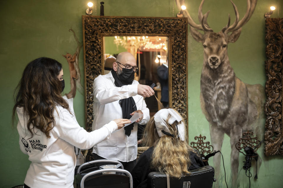 Marco Trapani is standing next to one of his first customers shortly after midnight in Dortmund, Germany early morning March 1, 2021. After about a two-and-a-half-month of closing to battle the coronavirus pandemic, the first hairdressers return to work at night night. (Bernd Thissen/dpa via AP)