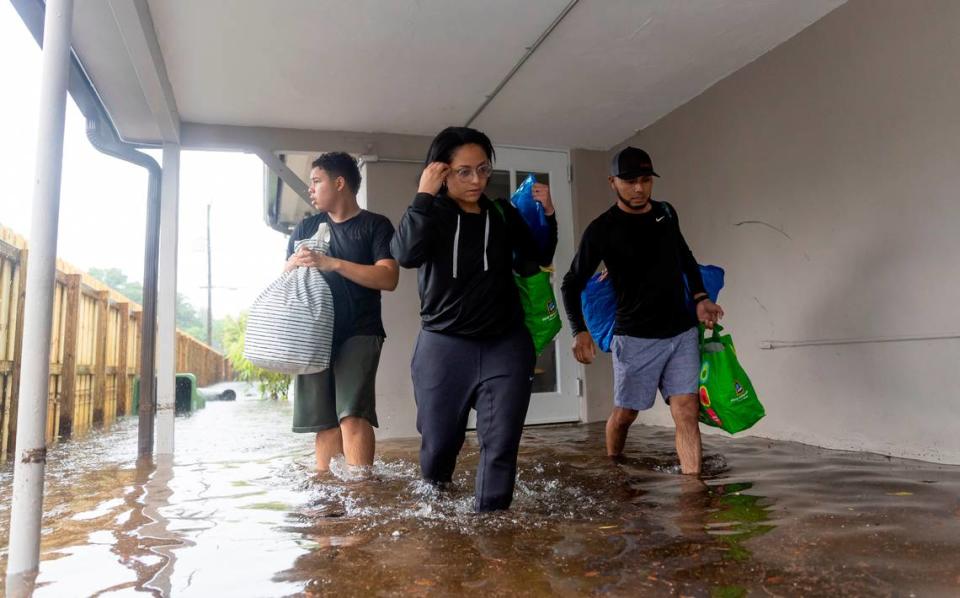 From left to right: Santiago Rojas, 15, Denis Mendez, 32, and Isain Lopez, 33, leave their partially submerged home in the Edgewood neighborhood on Thursday, April 13, 2023, in Fort Lauderdale, Fla. A torrential downpour severely flooded streets partially submerging houses and cars across South Florida.