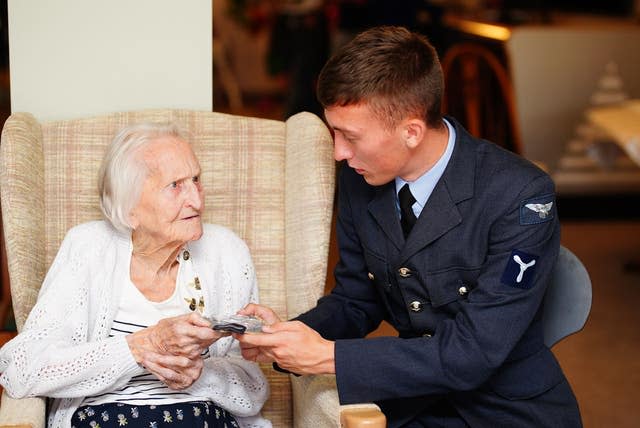 War veteran Peggy Terry is presented five wartime silver shillings by Air Specialist Class 1 William Anderson (Ben Birchall/PA)