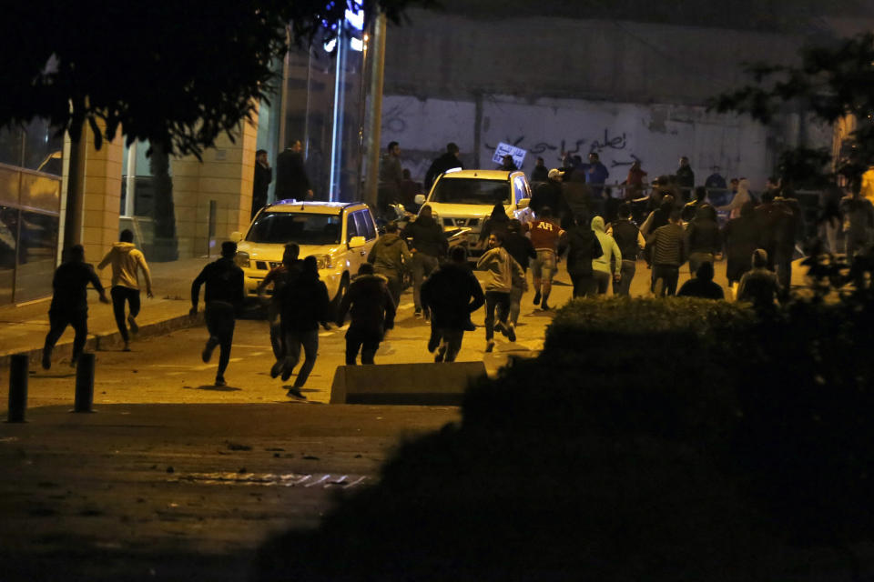 Supporters of the Shiite Hezbollah and Amal Movement groups, who are trying to attack the anti-government protesters, run away from tear gas that fire by Lebanese riot police, in Beirut, Lebanon, Wednesday, Dec. 11, 2019. Protesters are demanding a government made up of technocrats that would immediately get to work on the necessary reforms to address the economy. (AP Photo/Bilal Hussein)