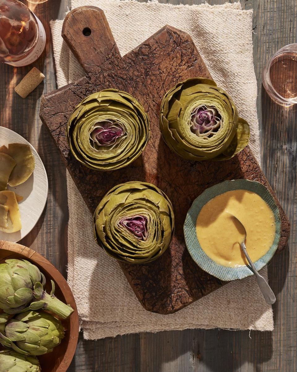 steamed artichokes with smoked paprika aioli on a wooden serving board