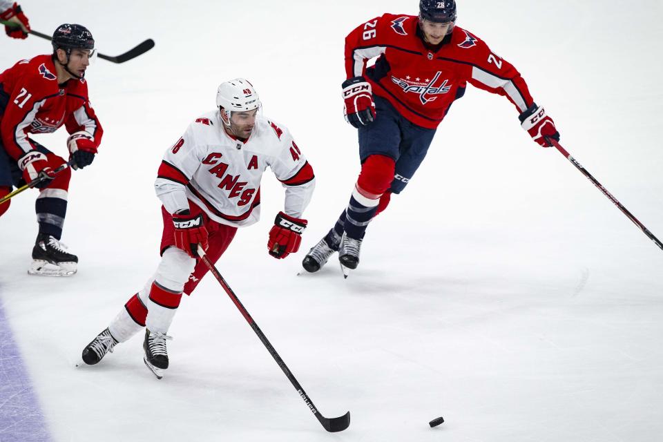 Carolina Hurricanes left wing Jordan Martinook (48), from Canada, skates with the puck as Washington Capitals right wing Garnet Hathaway (21) and center Nic Dowd (26) defend during the first period of an NHL hockey game, on Monday, Jan. 13, 2020, in Washington. (AP Photo/Al Drago)