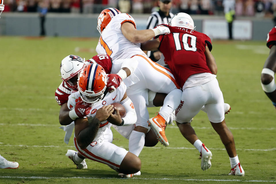 North Carolina State's Savion Jackson (90) tackles Clemson's D.J. Uiagalelei (5) as the left leg of Clemson running back Will Shipley (1) gets caught with North Carolina State's Tanner Ingle (10) also defending during the second half of an NCAA college football game in Raleigh, N.C., Saturday, Sept. 25, 2021. (AP Photo/Karl B DeBlaker)