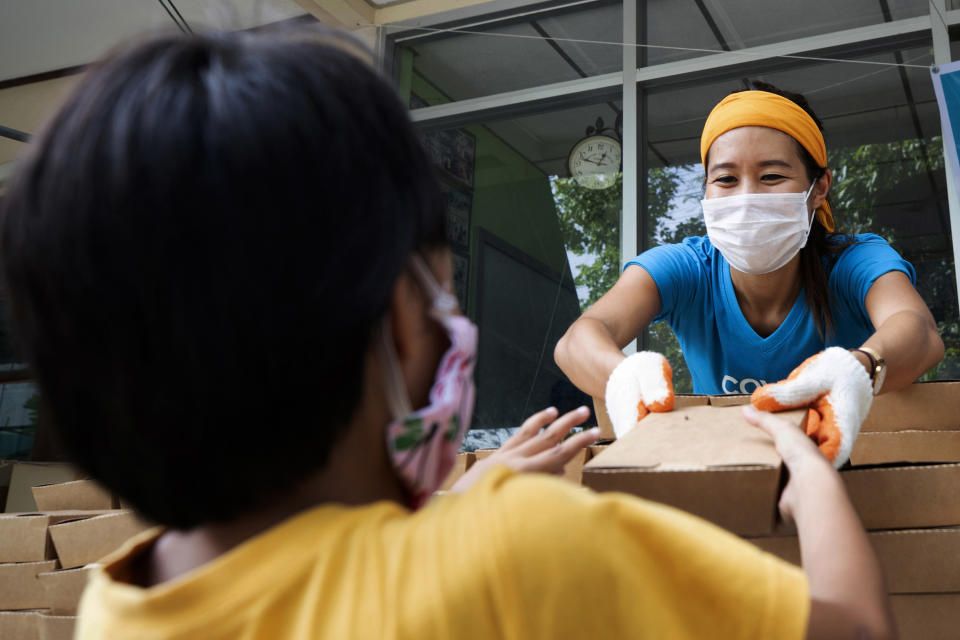 Founder of COVID Thailand Aid, Natalie Bin Narkprasert gives food to a boy at the railway-side community in Bangkok, Thailand Wednesday, June 10, 2020. Narkprasert, who runs a business in Paris, was stranded in her homeland by a flight ban, so she decided to use her skills to organize the network of volunteers, including Michelin-starred chefs, to help those in her homeland whose incomes were most affected by the pandemic restrictions.(AP Photo/Sakchai Lalit)