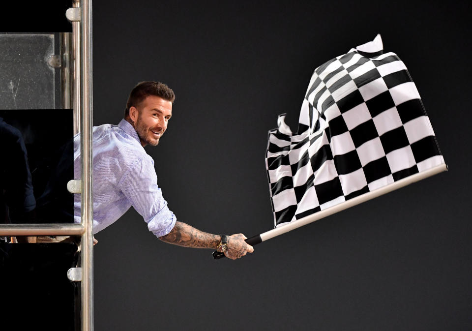 TOPSHOT - Former British football player David Beckham waves the checkered flag as Mercedes' British driver Lewis Hamilton crosses the finish line during the Formula One Bahrain Grand Prix at the Sakhir circuit in the desert south of the Bahraini capital Manama, on March 31, 2019. (Photo by Andrej ISAKOVIC / various sources / AFP)        (Photo credit should read ANDREJ ISAKOVIC/AFP/Getty Images)