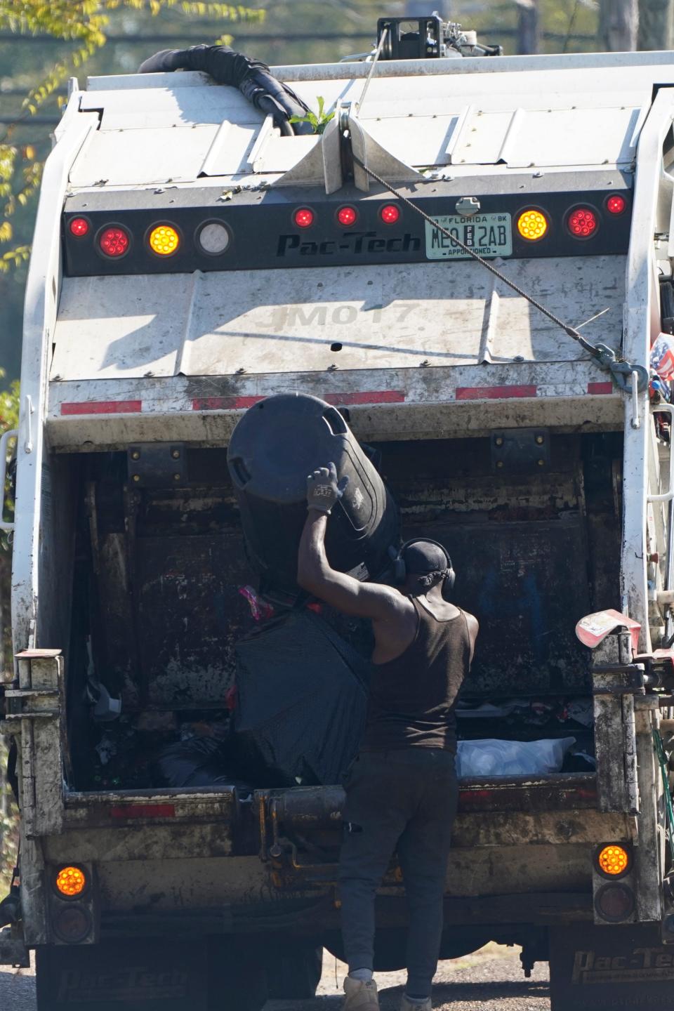 A Richard's Disposal employee dumps residential garbage into a rear loading trash truck, Friday morning, Oct. 7, 2022, in Jackson, Miss.