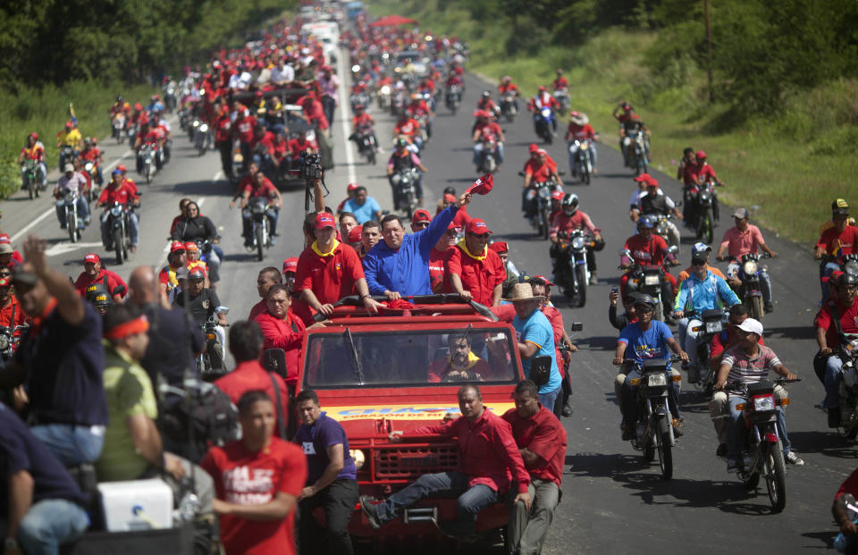 Venezuela's President Hugo Chavez waves to supporters from the top of a vehicle driven by Venezuela's Foreign Minister Nicolas Maduro during a campaign caravan from Barinas to Caracas, in Sabaneta, Venezuela, Monday, Oct. 1, 2012. Venezuela's presidential election is scheduled for Oct. 7. (AP Photo/Rodrigo Abd)