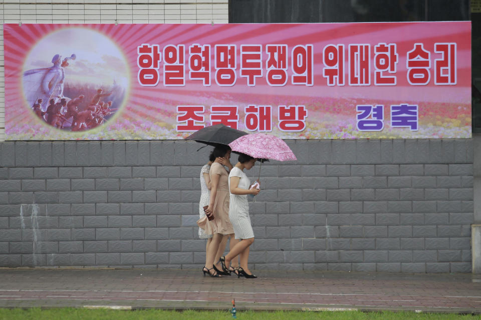 Citizens walk along Changjon Street past a festive poster reading "The great victory in the anti-Japanese revolutionary struggle" to commemorate the 77th anniversary of Korea's Liberation in Pyongyang, North Korea, Monday, Aug. 15, 2022. (AP Photo/Cha Song Ho)