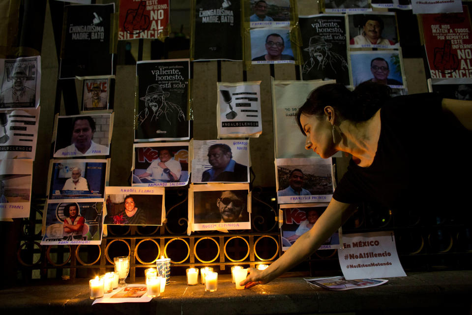 <p>A woman lays a candle in front of pictures of murdered journalists taped to a fence surrounding the Interior Ministry in Mexico City, Tuesday, May 16, 2017. (AP Photo/Rebecca Blackwell) </p>