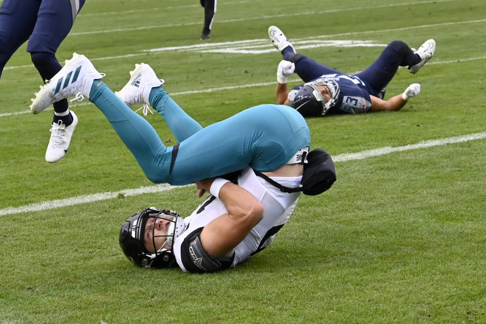 Jacksonville Jaguars quarterback Trevor Lawrence, left, scores past Tennessee Titans linebacker Dylan Cole (53) during the second half of an NFL football game Sunday, Dec. 11, 2022, in Nashville, Tenn. (AP Photo/Mark Zaleski)