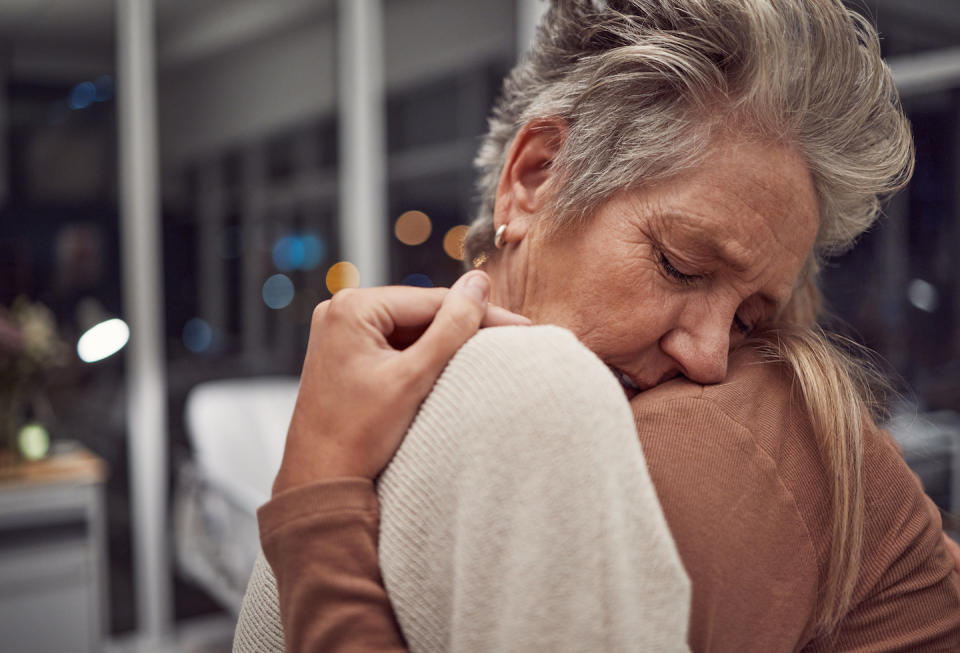 An elderly woman being hugged by another