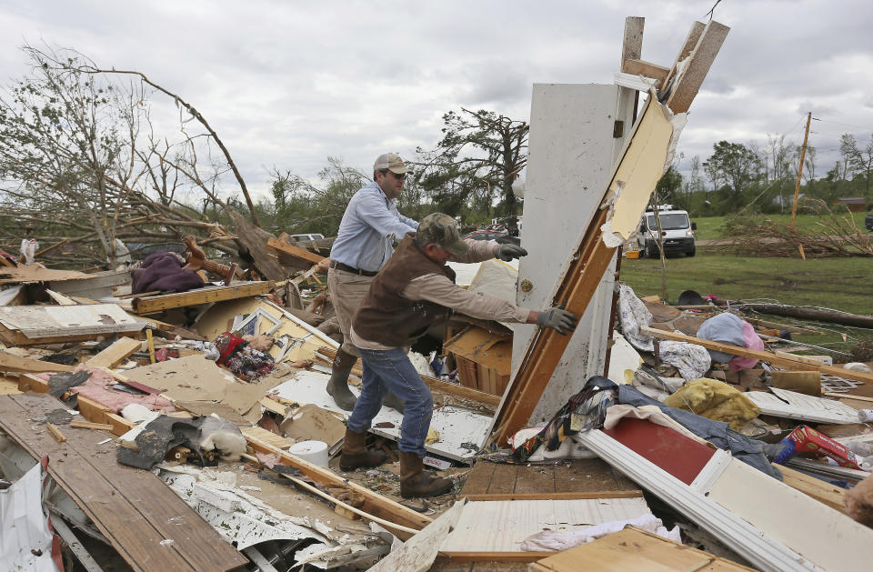 Roman Brown, left and Sam Crawford, right move part of a wall out of their way Sunday, April 14, 2019, as they help a friend look for their medicine in their destroyed home along Seely Drive outside of Hamilton, Miss. after an apparent tornado touched down Saturday night, April, 13, 2019. (AP Photo/Jim Lytle)