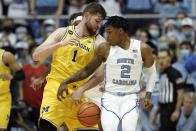 North Carolina guard Caleb Love (2) and Michigan center Hunter Dickinson (1) reach for the ball during the first half of an NCAA college basketball game in Chapel Hill, N.C., Wednesday, Dec. 1, 2021. (AP Photo/Gerry Broome)