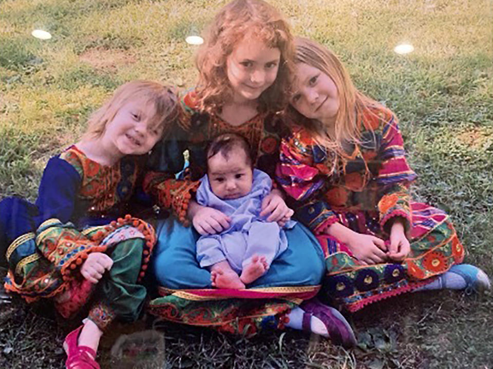 In this undated photo provided by Ryan Brummond, U.S. Special Forces Officer Ryan Brummond’s daughters pose with an Afghan interpreter's son wearing dresses that were gifted to them by Mohammad Khalid Wardak to celebrate the collective relationship between the men. Khalid, as he's called by his friends, had no intention of leaving Afghanistan, where he was a high-profile national police officer who'd worked alongside American special forces to defeat the Taliban. Then with stunning speed, his government collapsed. Now he is in hiding with his wife and four children, wounded and hunted by the Taliban, desperately hoping that American officials will repay his loyalty by helping his family escape almost certain death. (Ryan Brummond via AP)