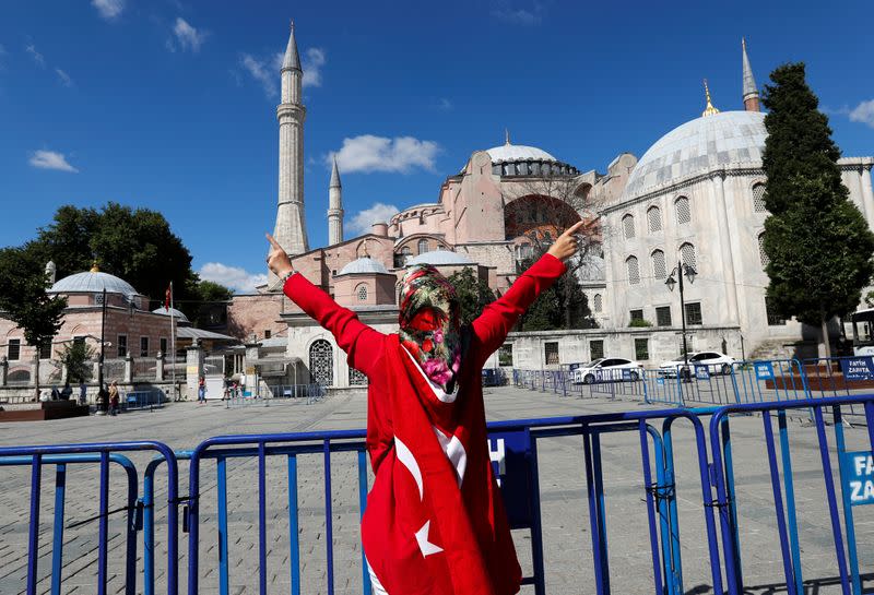 A woman gestures in front of the Hagia Sophia or Ayasofya, after a court decision that paves the way for it to be converted from a museum back into a mosque, in Istanbul