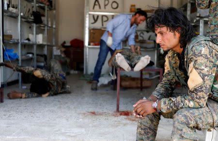 A Syrian Democratic Forces (SDF) fighter sit as medics treat his comrades injured by sniper fired by Islamic State militants in a field hospital in Raqqa, Syria June 28, 2017. REUTERS/Goran Tomasevic