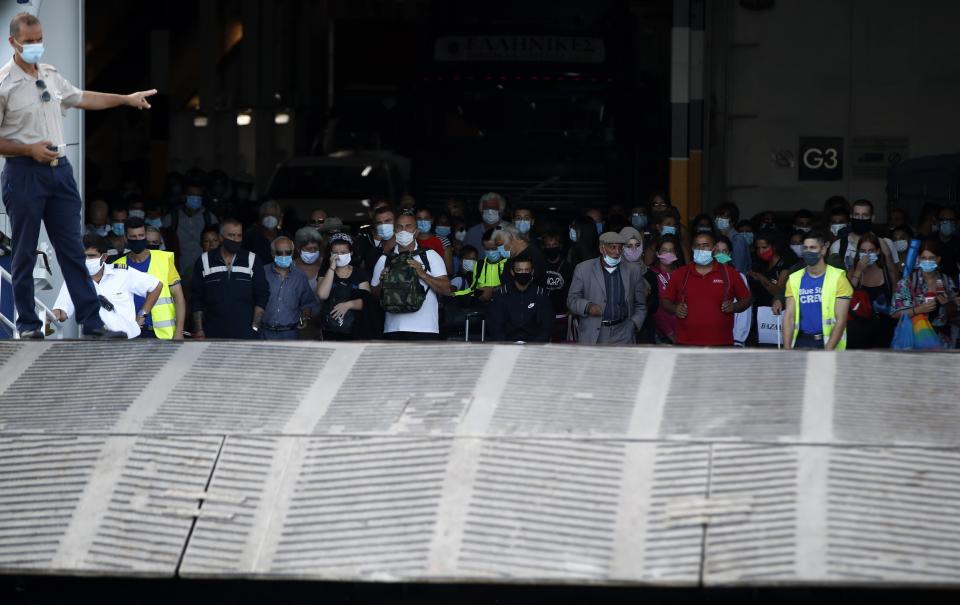 Travellers wearing face masks to protect against the spread of coronavirus, wait to disembark from a ferry at the port of Piraeus, near Athens, Thursday, Aug. 20, 2020. Authorities in Greece are using free on-the-spot tests for ferry passengers and nightlife curfews on popular islands to stem a resurgence of the coronavirus after the country managed to dodge the worst of the pandemic. The number of confirmed virus cases and deaths in Greece remains lower than in many other European countries. (AP Photo/Thanassis Stavrakis)