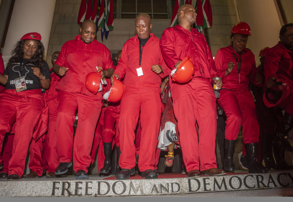 Leader of the Economic Freedom Fighters (EFF) party Julius Malema, center, and his members dance on the steps of parliament after walking out of Parliament at the State of the Nation Address in Cape Town, South Africa, Thursday, Feb. 13, 2020. (Brenton Geach/Pool Photo via AP)