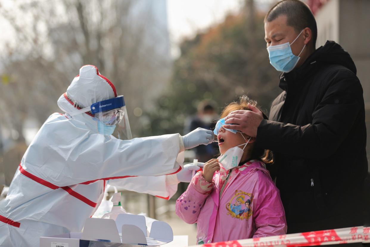 A medical staff member (L) collects sample from a girl for a nucleic acid test for the COVID-19 coronavirus at a residental area in Wuhan in China's central Hubei province on March 5, 2020. - China on March 5 reported 31 more deaths from the COVID-19 coronavirus epidemic, taking the country's overall toll past 3,000, with the number of new infections slightly increasing. (Photo by STR / AFP) / China OUT (Photo by STR/AFP via Getty Images)
