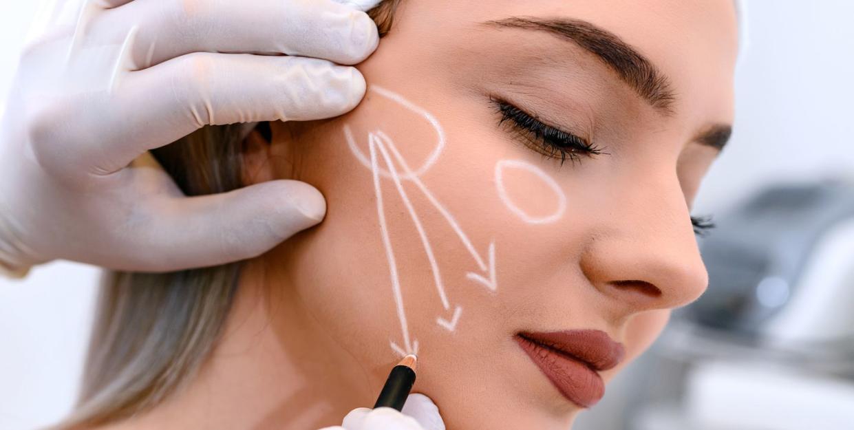 beautician draw correction lines on woman face