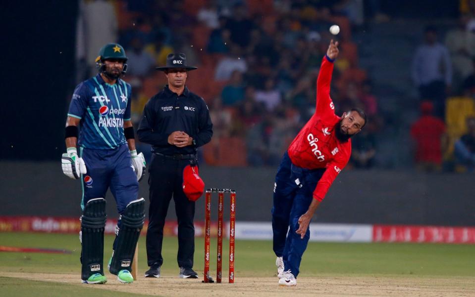 England's Adil Rashid, right, bowls as Pakistan's Iftikhar Ahmed, left, and umpire Rashid Riaz - AP Photo/K.M. Chaudary