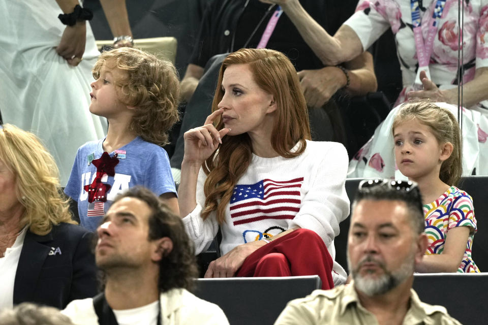 Jessica Chastain, centro con un suéter con la bandera de Estados Unidos, asiste a la ronda de clasificación de gimnasia artística femenina en la Arena Bercy de los Juegos Olímpicos de Verano de 2024, el domingo 28 de julio de 2024, en París, Francia. (Foto AP/Charlie Riedel)