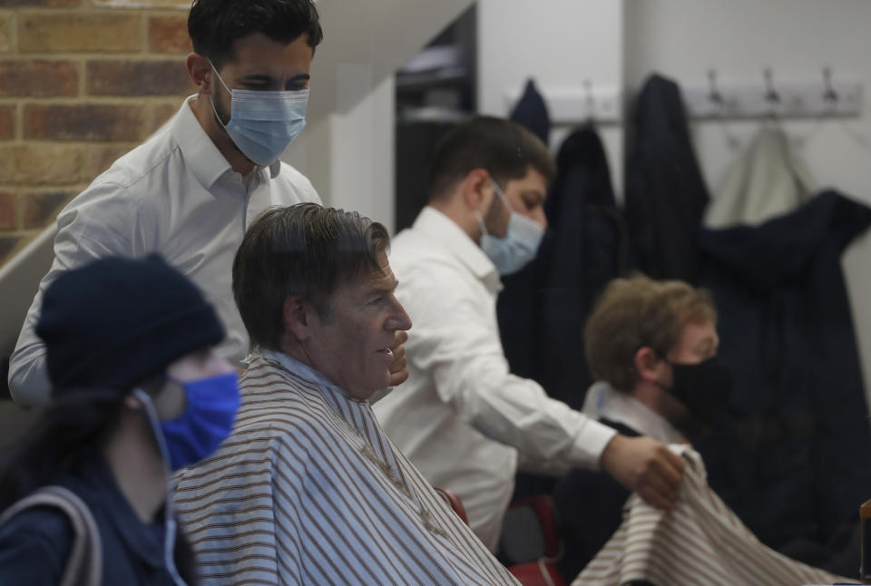 The Lord Mayor of London William Russell gets his hair cut by Ali Baltar, owner of the Grooming Lounge in the City of London, Monday, April 12, 2021. Millions of people in England will get their first chance in months for haircuts, casual shopping and restaurant meals on Monday, as the government takes the next step on its lockdown-lifting road map. (AP Photo/Alastair Grant)