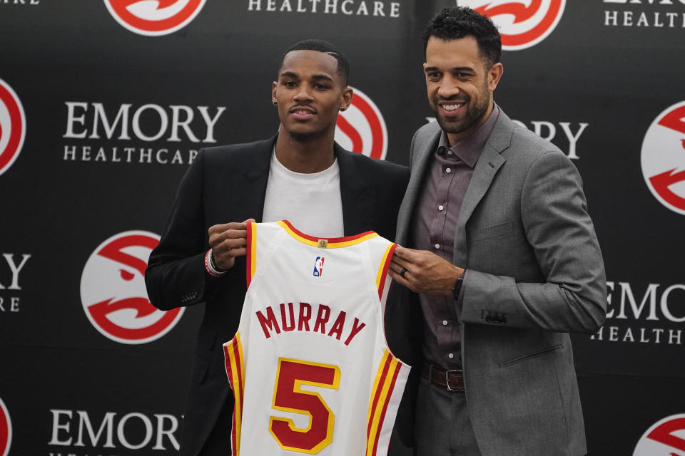 FILE - Newly acquired NBA basketball team Atlanta Hawks guard Dejounte Murray, left, and general manager Landry Fields pose with Murray's jersey during a news conference July 1, 2022, in Atlanta. Murray provides the Hawks with another ball-handling guard who can play the point, giving guard Trae Young a chance to work more without the ball. (AP Photo/John Bazemore, File)