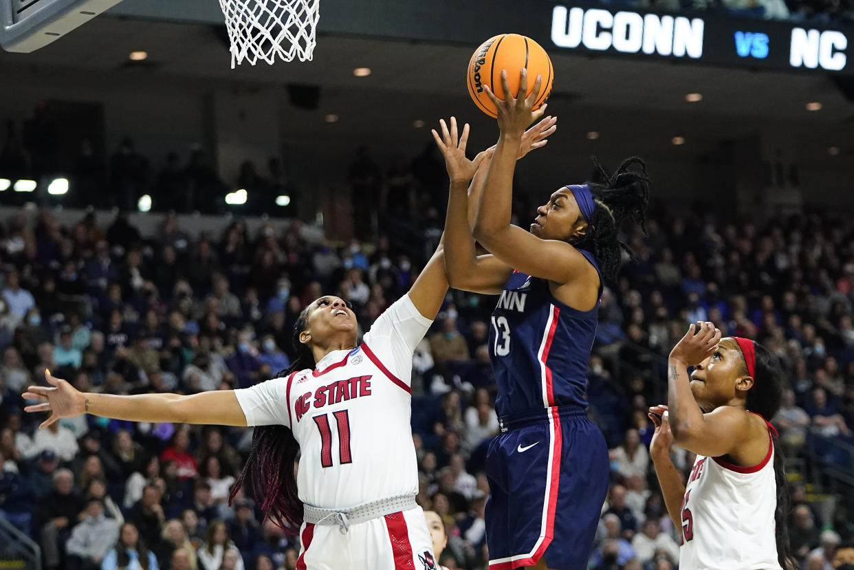 Connecticut guard Christyn Williams (13) puts up a shot against NC State forward Jakia Brown-Turner (11) and forward Kayla Jones (25) during the first quarter of the East Regional final college basketball game of the NCAA women's tournament, Monday, March 28, 2022, in Bridgeport, Conn. (AP Photo/Frank Franklin II)