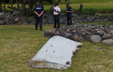 French gendarmes and police stand near a large piece of plane debris which was found on the beach in Saint-Andre, on the French Indian Ocean island of La Reunion, July 29, 2015. REUTERS/Zinfos974/Prisca Bigot
