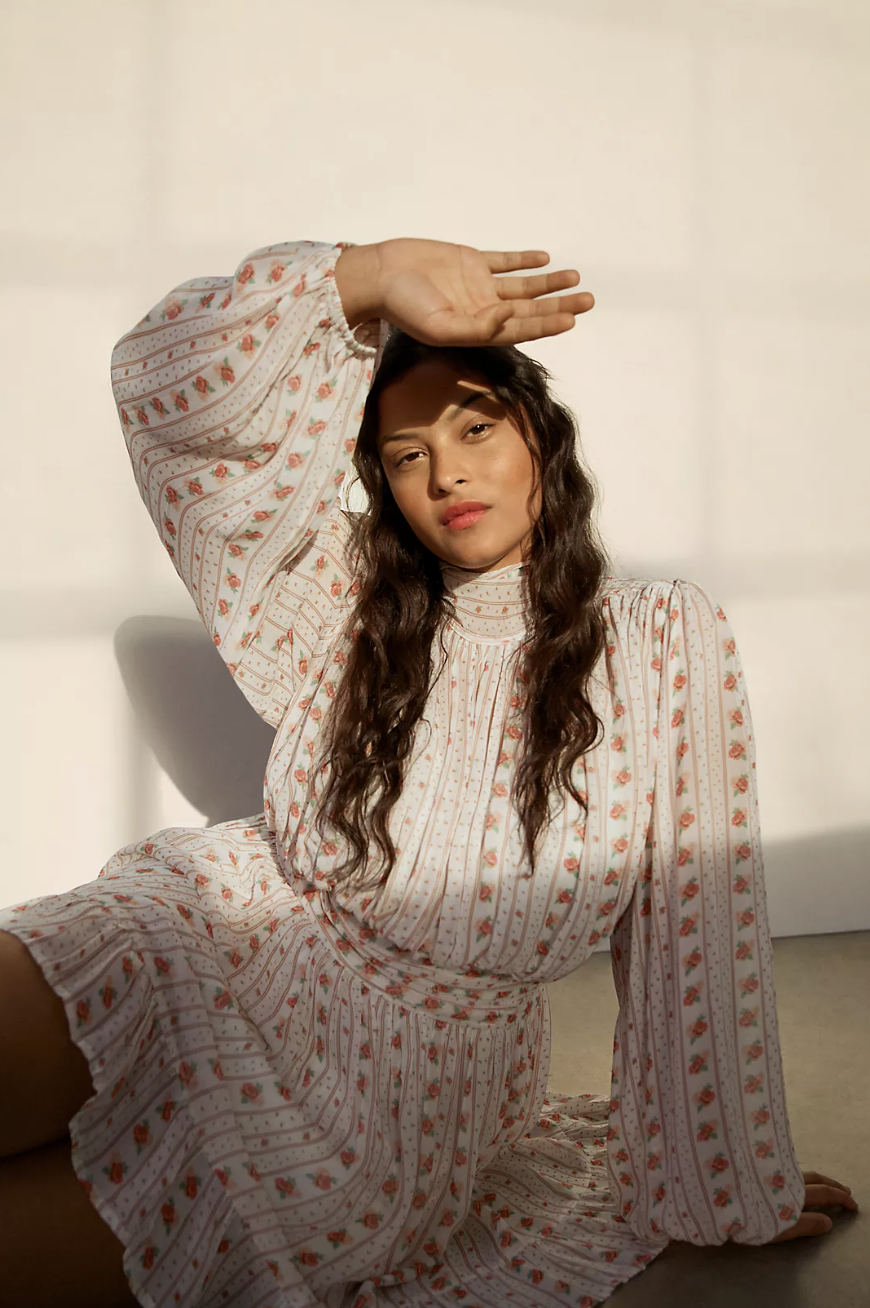 model sitting on floor with hand over face wearing Let Me Be Mock Neck Sheer Mini Dress (Photo via Anthropologie)