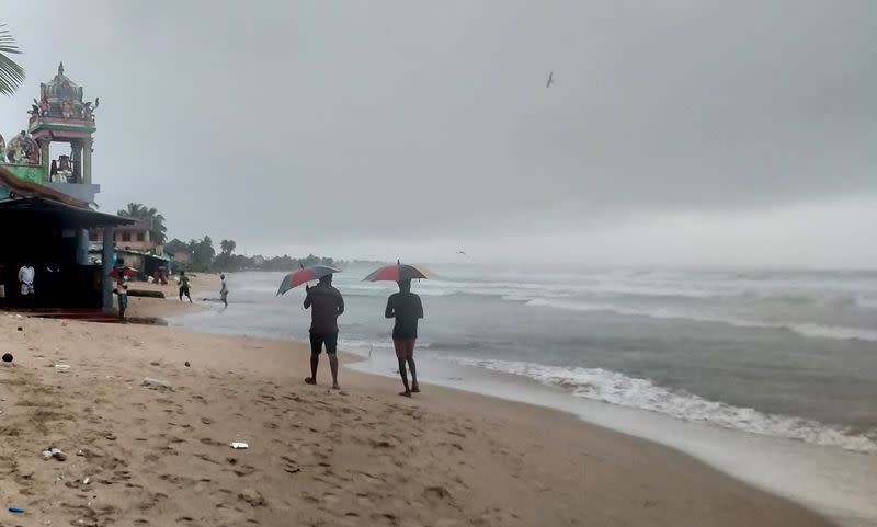 Two men walk along a beach as Cyclone Burevi is expected to near the coast of Trincomalee