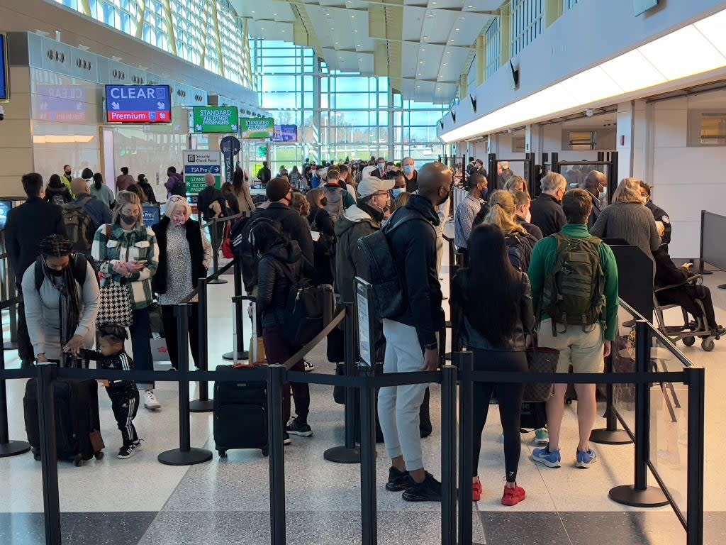 Travellers stand in line at a security checkpoint at Washington National Airport in Arlington, Virginia, on 24 November (AFP via Getty Images)