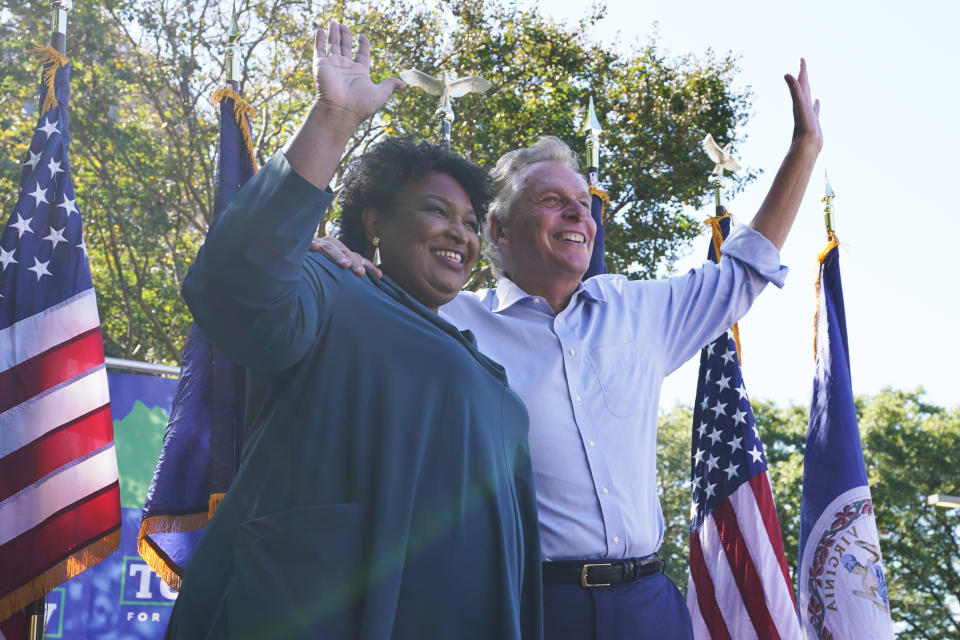 Voting rights activist Stacey Abrams, left, waves to the crowd with Democratic gubernatorial candidate, former Virginia Gov. Terry McAuliffe, right, during a rally in Norfolk, Va., Sunday, Oct. 17, 2021. Abrams was in town to encourage voters to vote for the Democratic gubernatorial candidate in the November election. (AP Photo/Steve Helber)