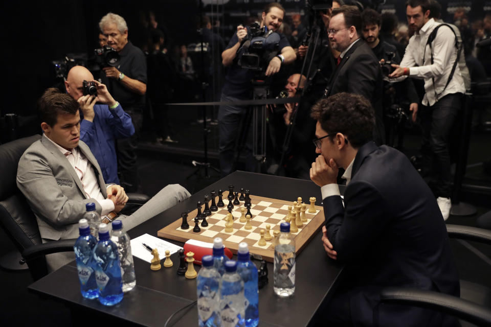 Reigning chess world champion Magnus Carlsen, left, from Norway, plays Italian-American challenger Fabiano Caruana in the first few minutes of round 12 of their World Chess Championship Match in London, Monday, Nov. 26, 2018. (AP Photo/Matt Dunham)