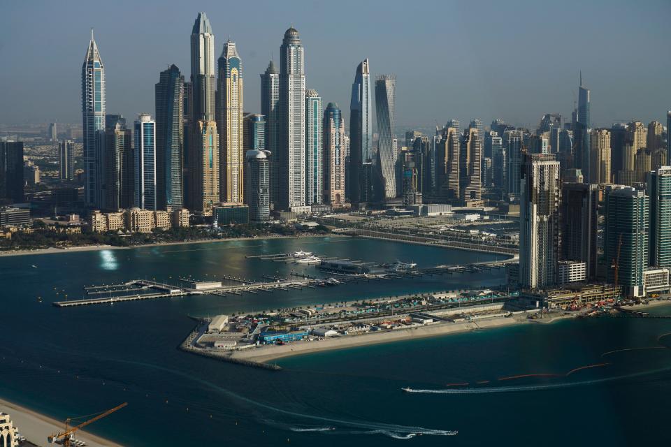 A boat and jet skis ride the waves in front of the Dubai Marina in Dubai, United Arab Emirates, Monday, July 19, 2021.