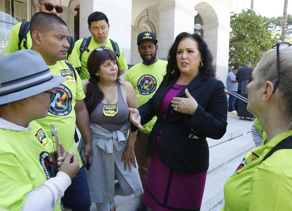 Assemblywoman Lorena Gonzalez, D-San Diego, second from right, talks with members of Rideshare Drivers United, who support her measure to limit when companies can label workers as independent contractors, which was approved by a Senate committee, in Sacramento, Calif., Wednesday, July 10, 2019. Her bill, AB5, aimed at major employers like Uber and Lyft, still needs approval by the full Senate. (AP Photo/Rich Pedroncelli)