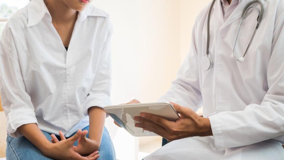 A woman sits next to a doctor