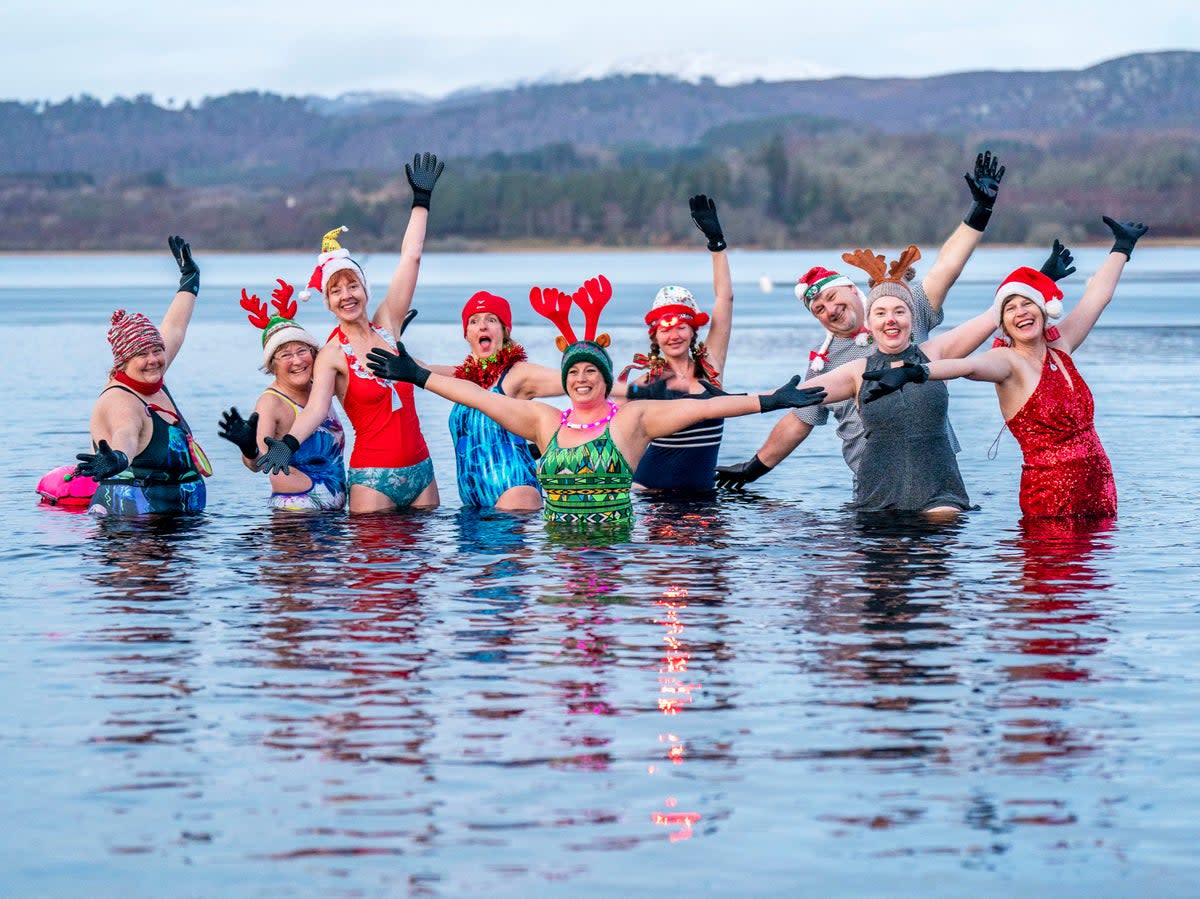 Members of the Loch Insh Dippers wild swim group take part in a Christmas-themed swim in Loch Insh in the Cairngorms National Park near Aviemore, Scotland (PA)