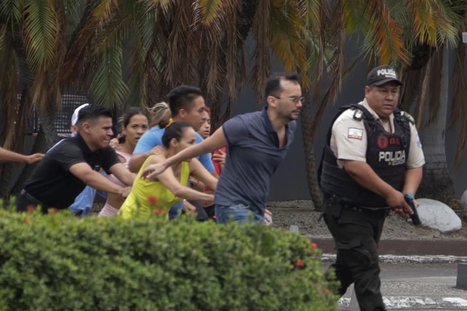 Police evacuate staff from the TC television channel station after a group of armed men broke onto their set during a live broadcast, in Guayaquil, Ecuador, Tuesday, Jan. 9, 2024.