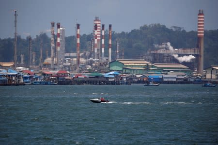 People sit on a boat driving through Balikpapan bay in East Kalimantan province