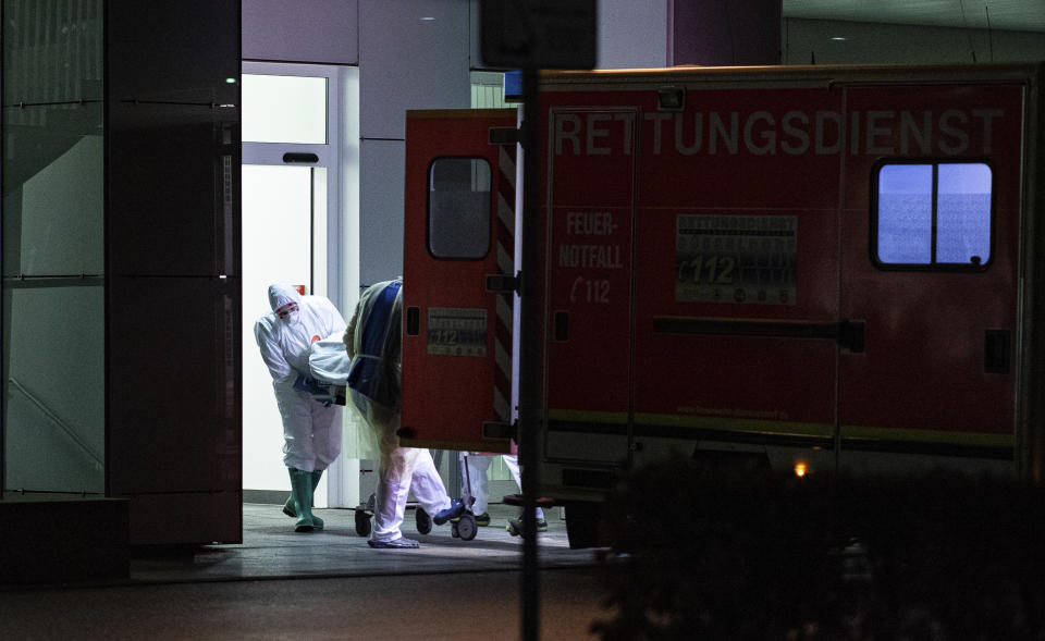 Medical staff in carry the first person infected with the coronavirus in the German state of North Rhine Westphalia out of an ambulance into the Infection Center of the University Hospital in Duesseldorf, Germany, Wednesday, Feb 26, 2020. (Guido Kirchner/dpa via AP)