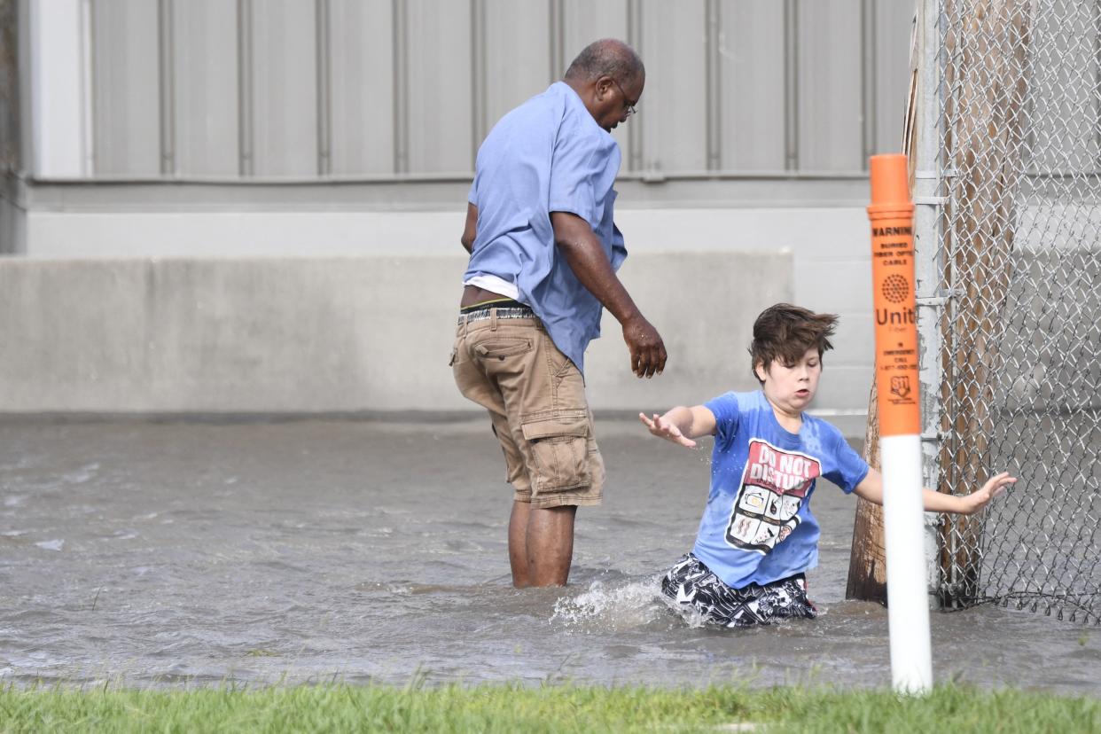 A man and child wade through water 