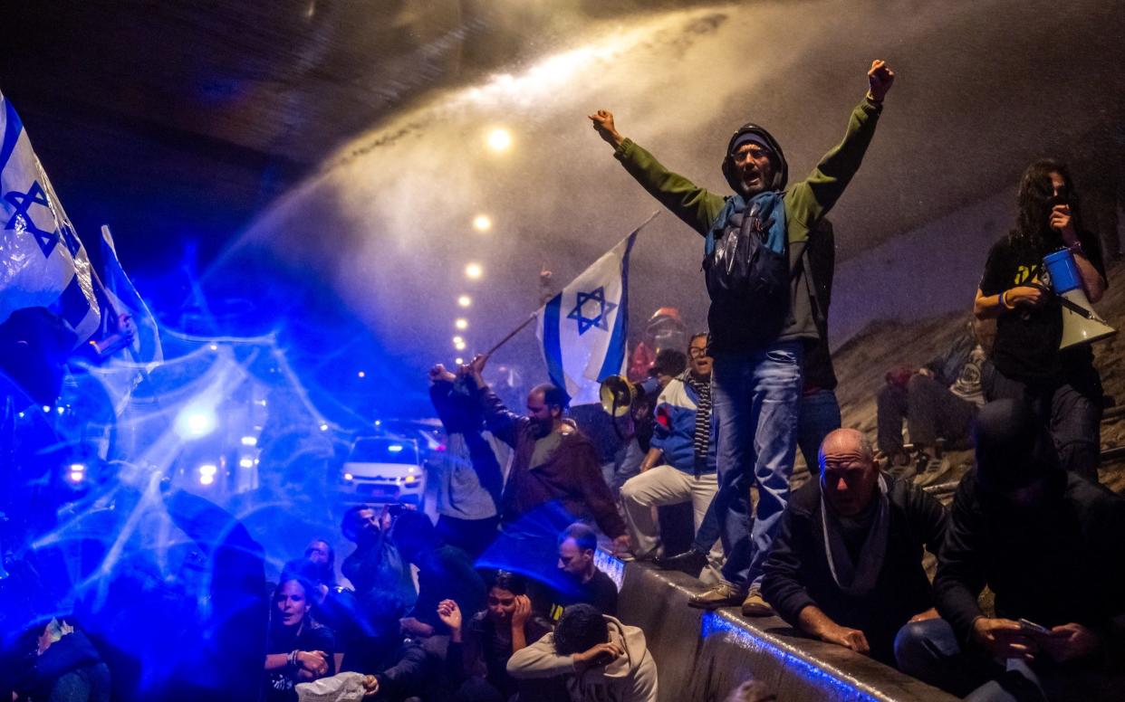 Police spray a water cannon and clash with anti-government protesters blocking a part of the Ayalon Highway