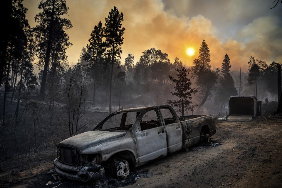 FILE - The Oak Fire burns behind a scorched pickup truck in the Jerseydale community of Mariposa County, Calif., early July 24, 2022. (AP Photo/Noah Berger, File)