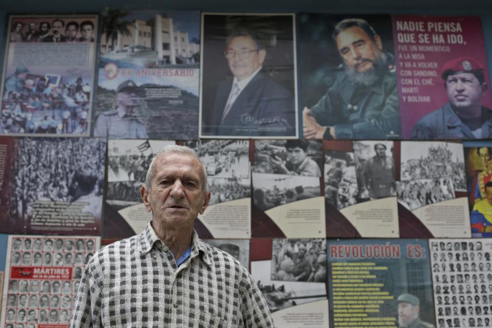 Alejandro Ferras Pellicer, 94, a veteran of the 1953 assault on the Moncada military barracks, stands in front of pictures of Cuba's President Raul Castro, Cuban former president Fidel Castro and Venezuela's late president Hugo Chavez at the Sitial Moncada (Moncada Site) in Havana December 27, 2014. Cuba's most prominent dissidents say they have been kept in the dark by U.S. officials over a list of 53 political prisoners who will be released from jail as part of a deal to end decades of hostility between the United States and Cuba. Picture taken December 27, 2014. REUTERS/Enrique De La Osa (CUBA - Tags: POLITICS SOCIETY)