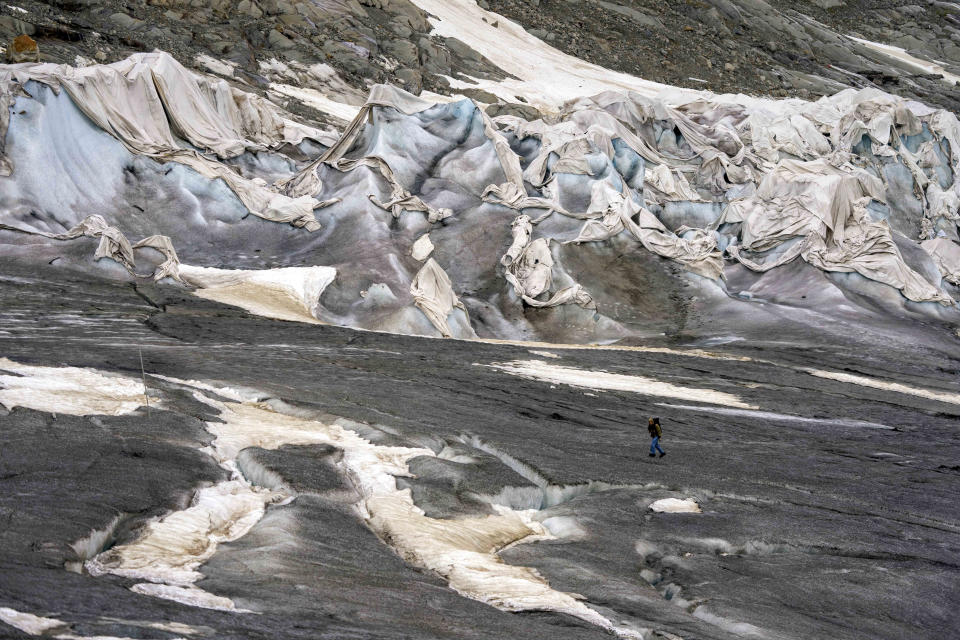 FILE - A team member of Swiss Federal Institute of Technology glaciologist and head of the Swiss measurement network 'Glamos', Matthias Huss, passes the Rhone Glacier covered by sheets near Goms, Switzerland, Friday, June 16, 2023. A top glacier watcher has warned that a warm early summer and a heat wave last week could have caused severe glacier melt across Switzerland, threatening to make 2023 the second-worst year for ice loss after a record thaw last year. (AP Photo/Matthias Schrader, File)