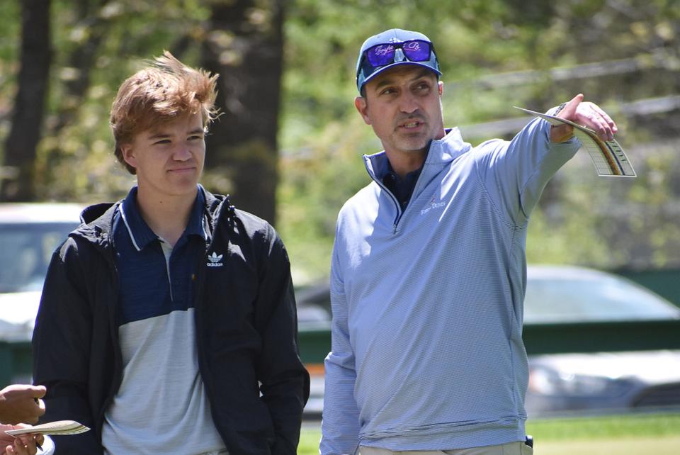 Hartland golf coach Nathan Oake gives pointers to Ryan Bohlen during a tournament last spring.